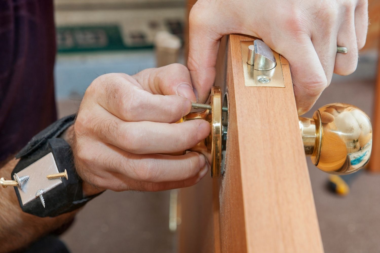 A close up of a person adding a door knob to a new exterior door. 