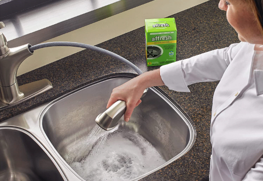 woman cleaning garbage disposal with cleaning product on the counter