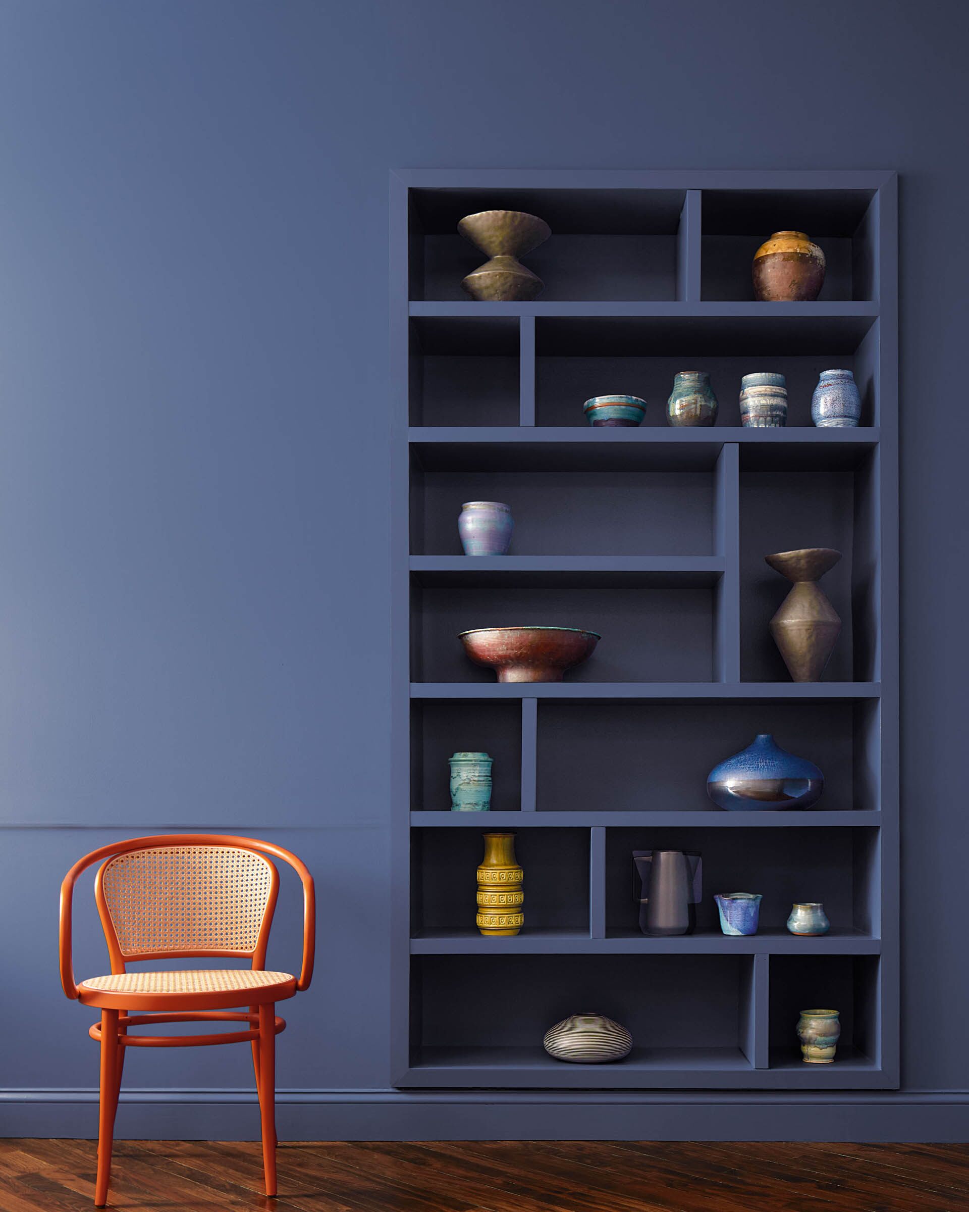 Wall and bookshelf painted in Blue Nova paint with an accent chair.