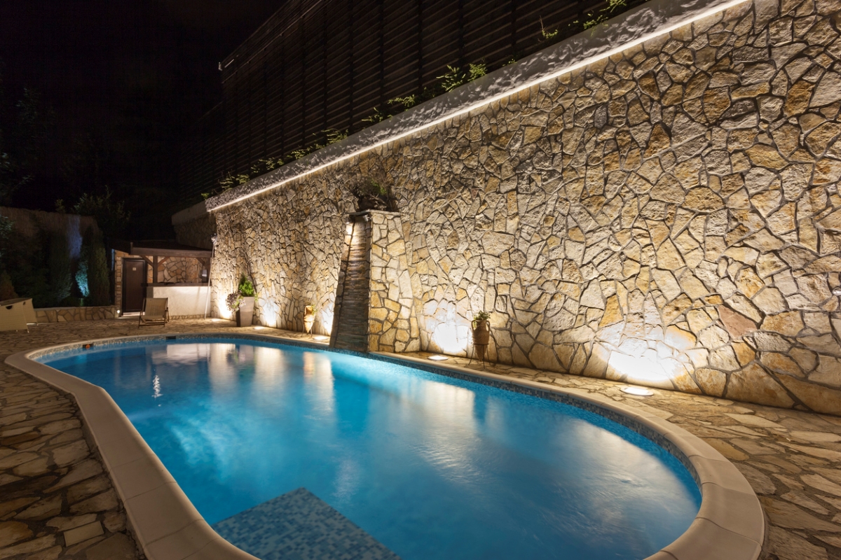 A pool with in-ground lights in the stone deck area. 