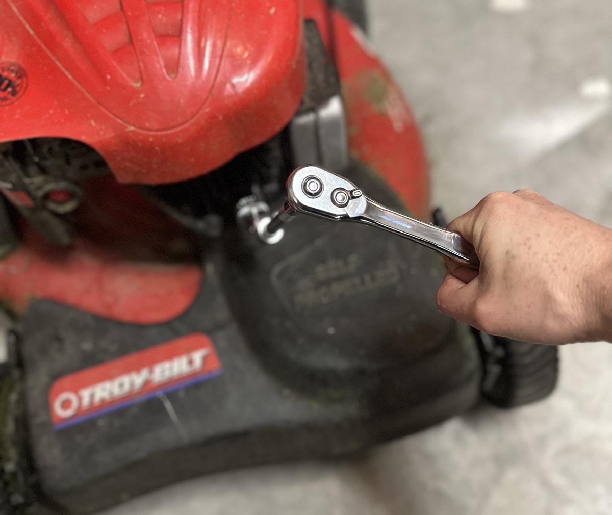 A person making an adjustment on a lawn mower using the DeWalt mechanics tool set