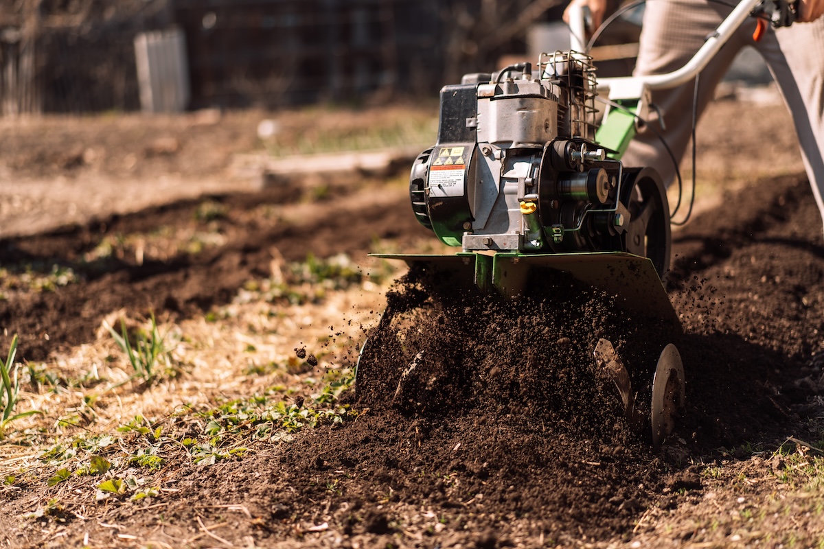 Green garden cultivator grinding up garden soil.