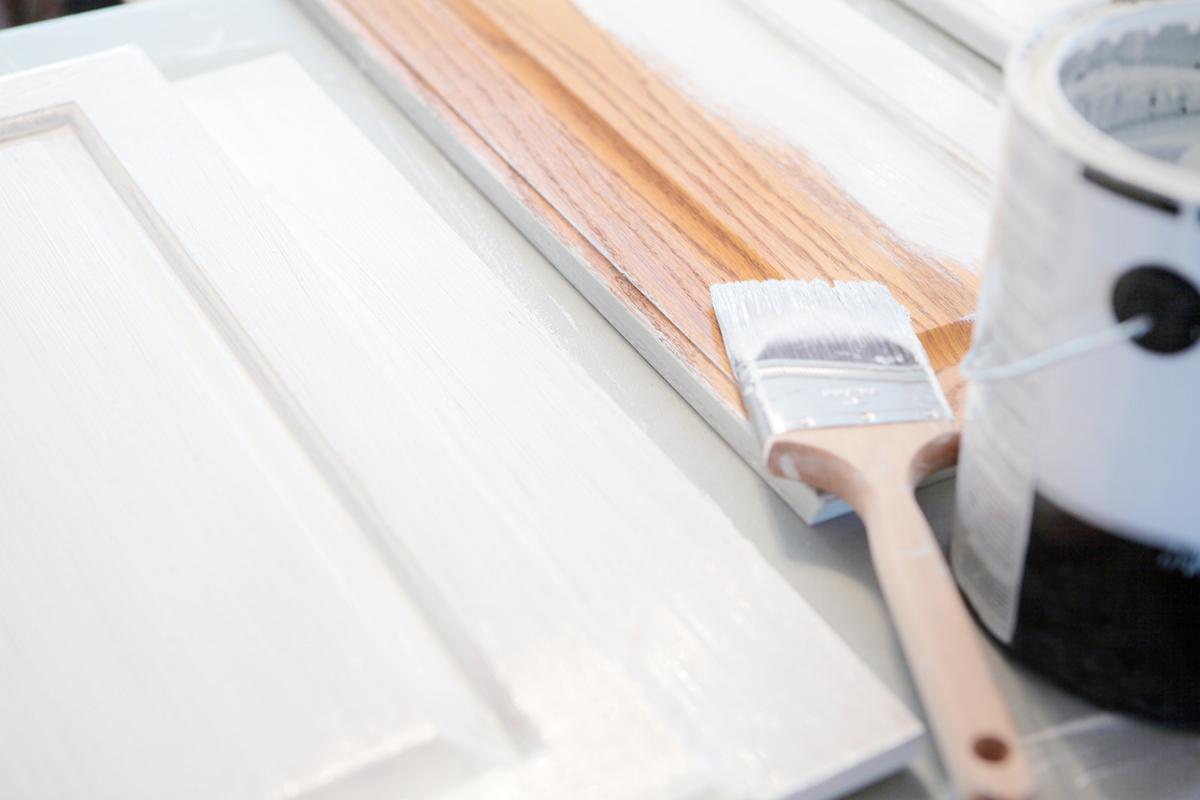 peinture blanche à faible teneur en COV sur armoires en bois avec pinceau humide et pot de peinture