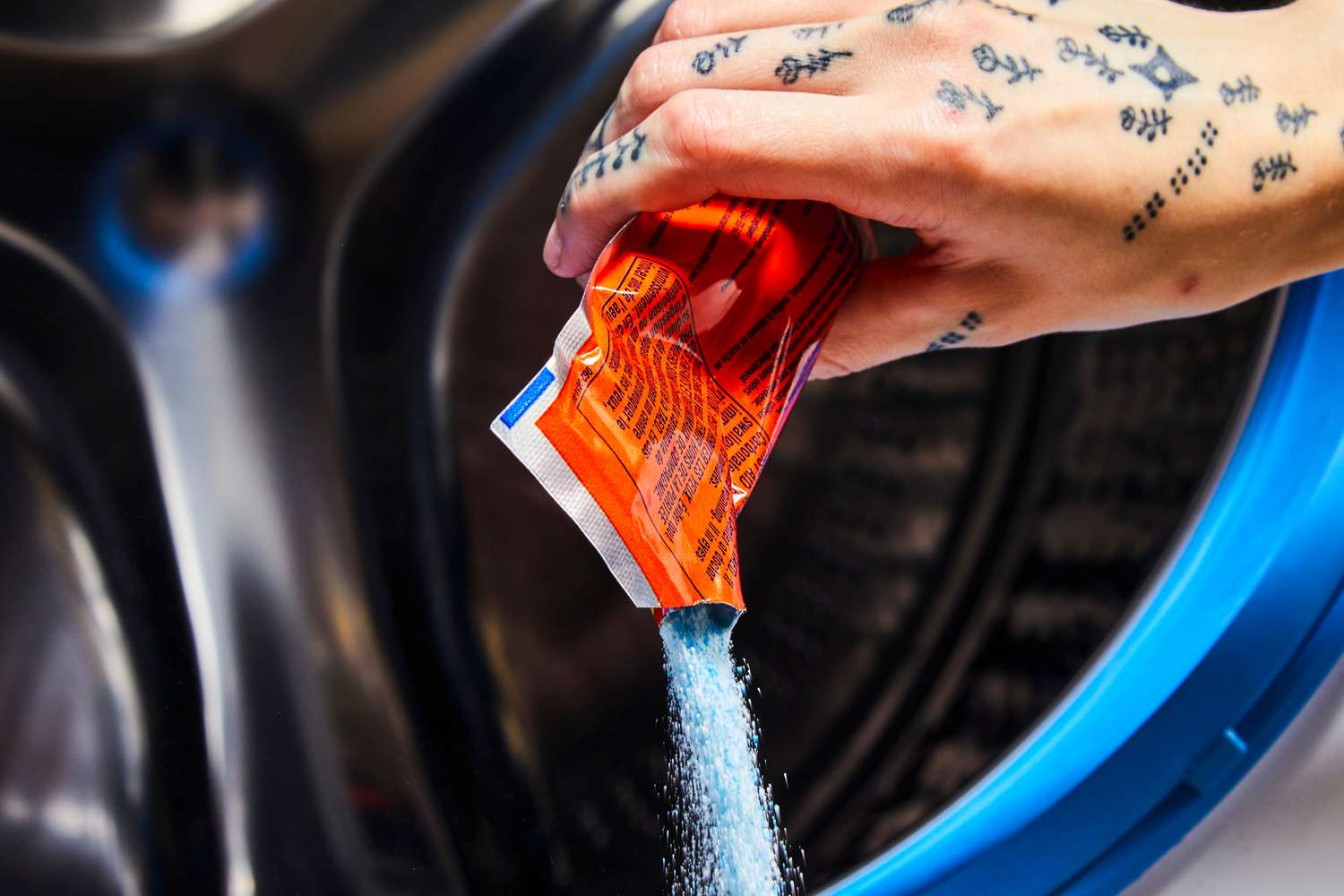 A hand pouring the Tide Washing Machine Cleaner with Oxi into a washing machine.