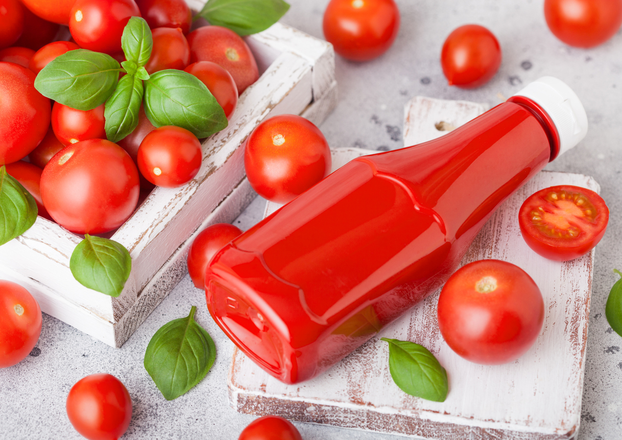 Unlabeled ketchup bottle next to several fresh cherry tomatoes