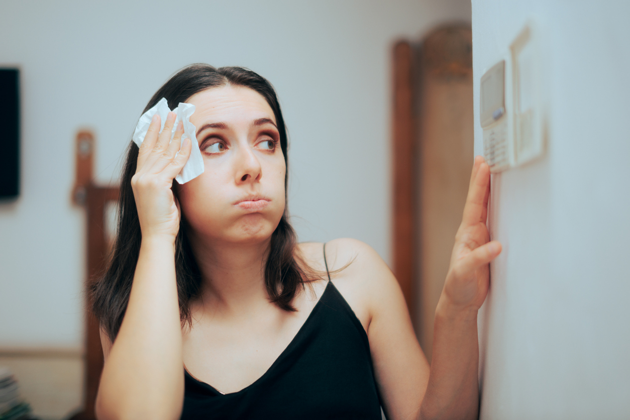 woman adjusting thermostat because she is hot