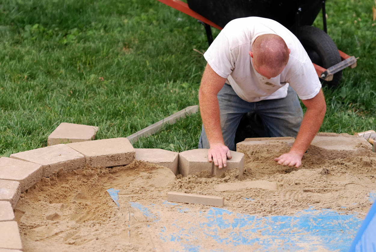 A worker is in the process of building a retaining wall.