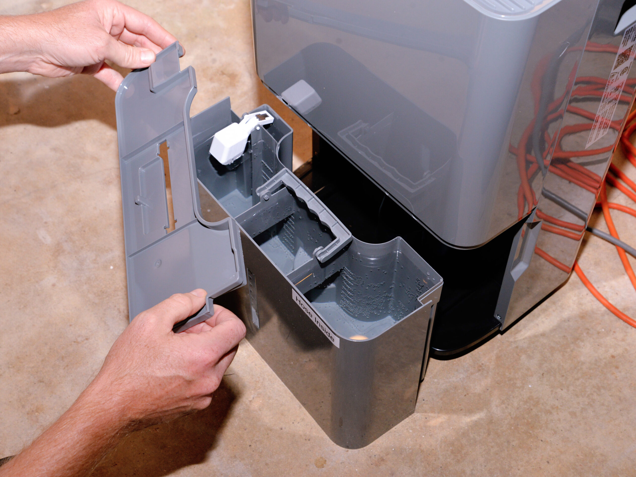 Person pulling bucket out of dehumidifier to see i it needs to be emptied