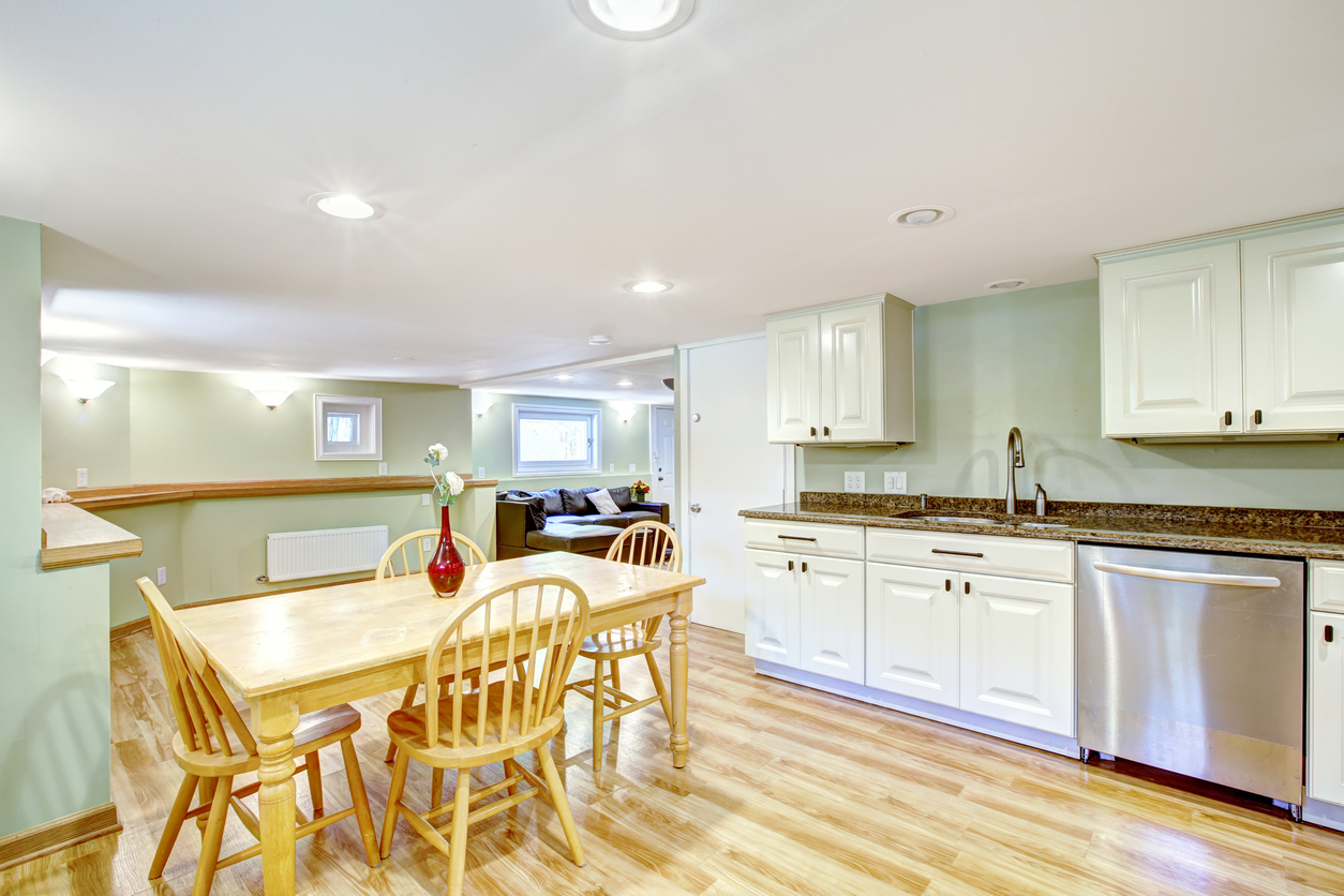 Basement kitchen room with rustic dining table set in Mother-in-law apartment. Light mint tones of wall blent with white kitchen cabinets