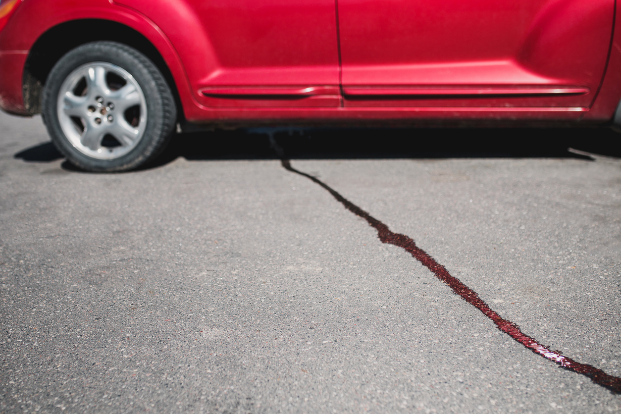 A stream of liquid on the pavement from under the car - oil flows from the engine