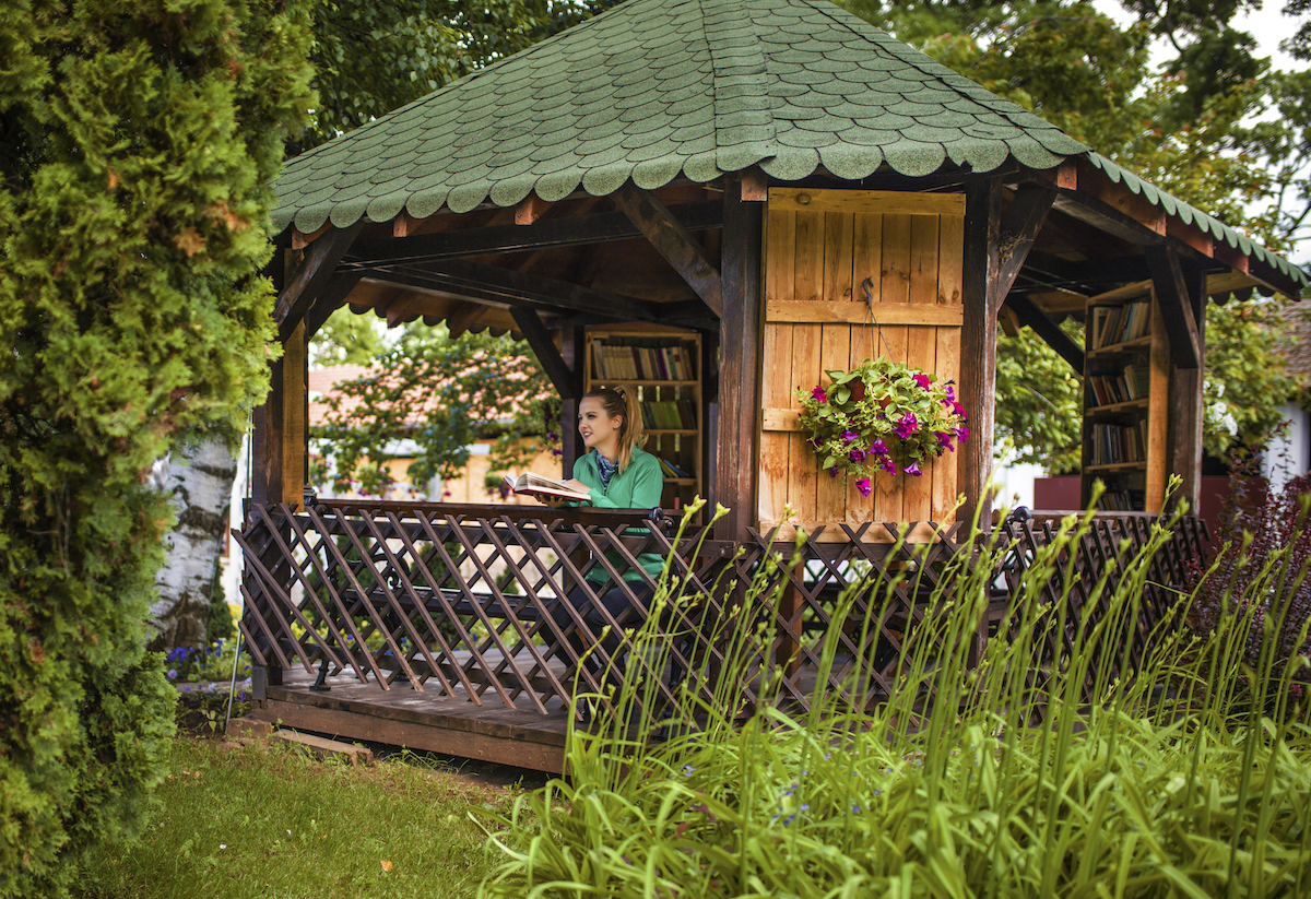 A woman is holding a book while standing inside of a gazebo filled with books on the walls.