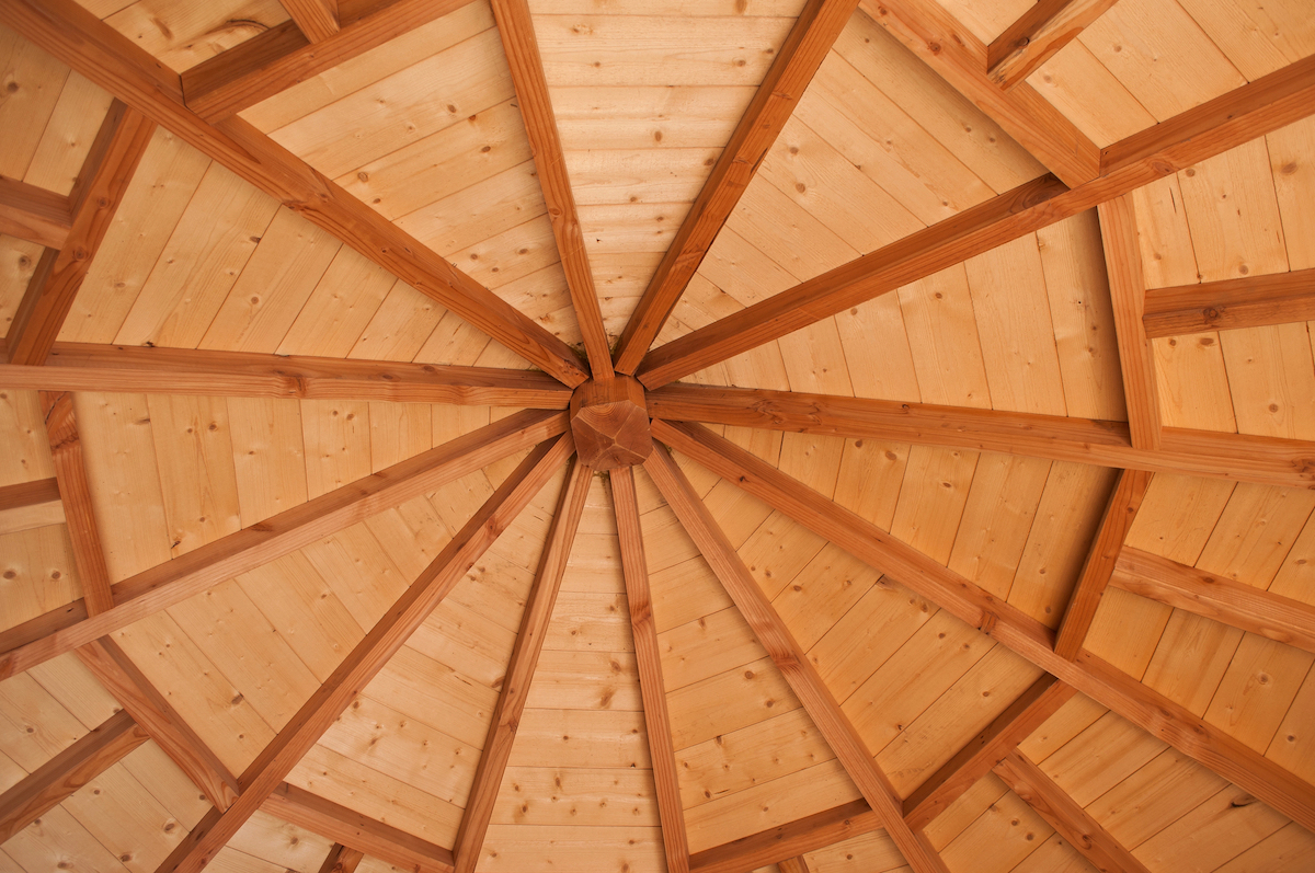 The interior of a gazebo is made of contrasting wood.