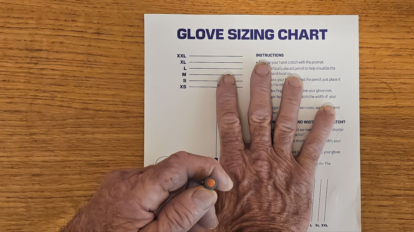 Person using a Vermont Gloves size chart to measure hands