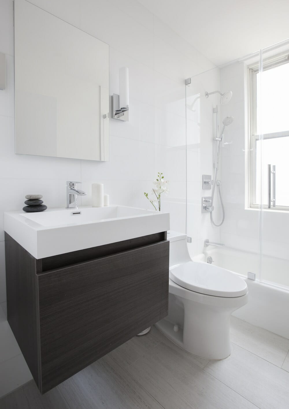 A small white bathroom with a wooden vanity under a white porcelain sink.