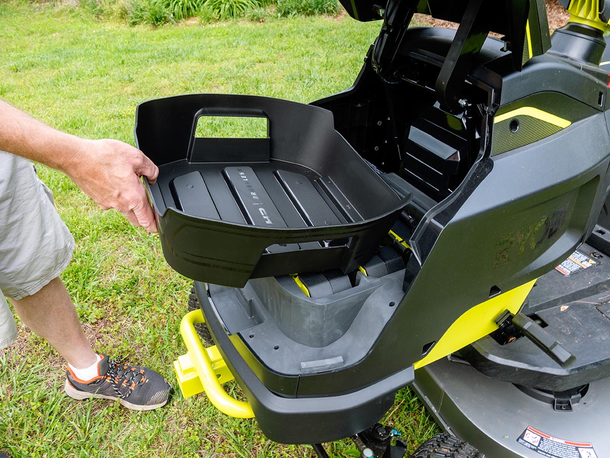 Person removing rear storage container from Ryobi lawn tractor